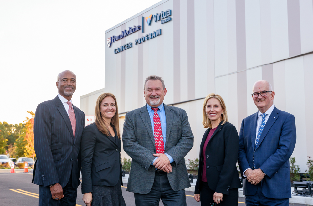 Executives stand in front of the Penn Medicine | Virtua Health Proton Therapy Center